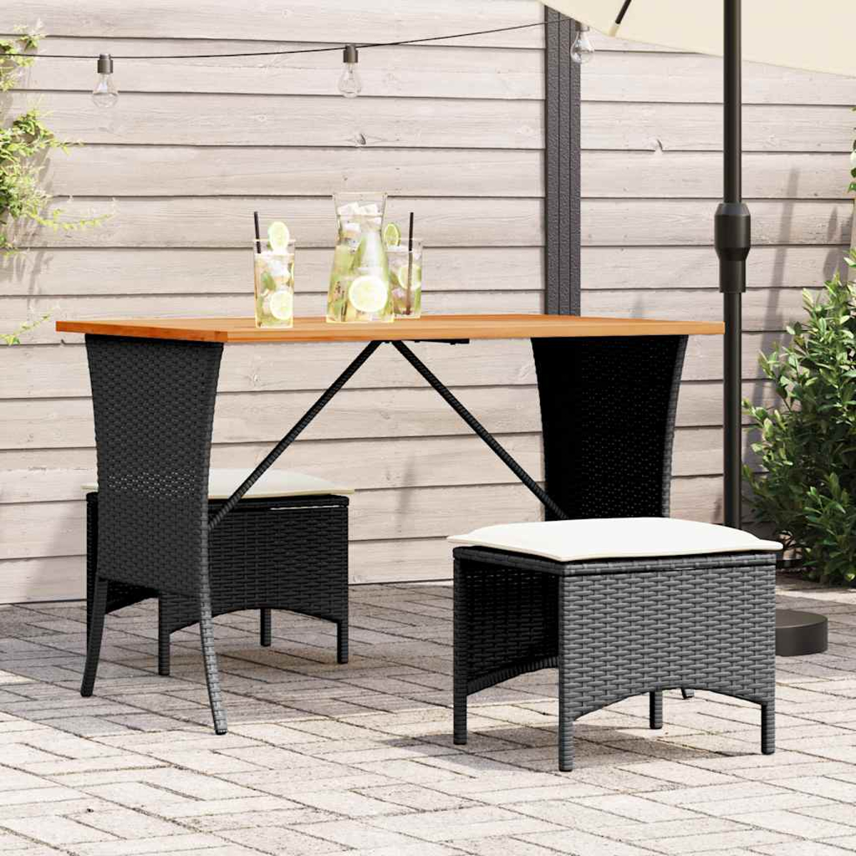 Arredamento esterno: tavolo con bevande, sedie nere e sgabello abbinato. Patio con parete in legno sullo sfondo.