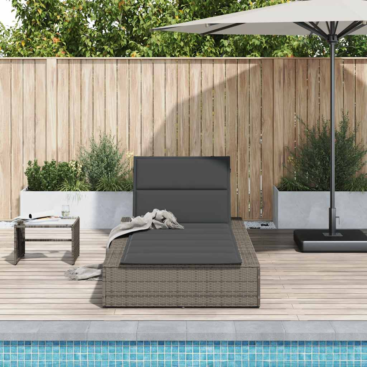 Outdoor-Liegestuhl mit grauem Kissen. Holzterrasse. Schwimmbad im Hintergrund.