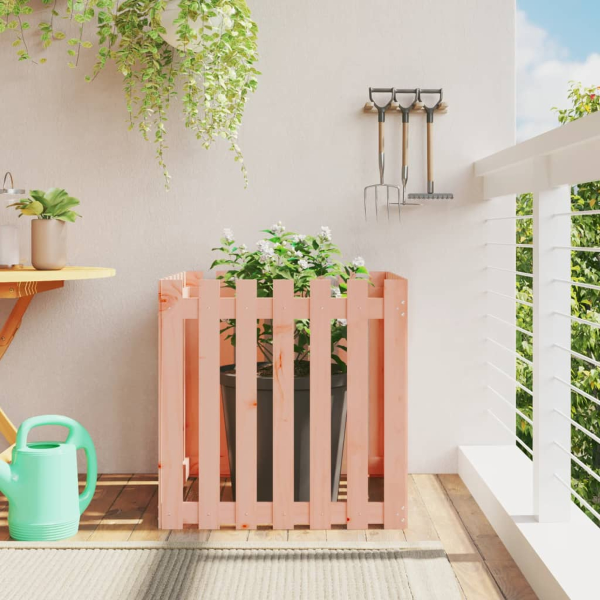 Rosa Holzzaun mit Topfpflanze auf einem Balkon, mit Gartengeräten.