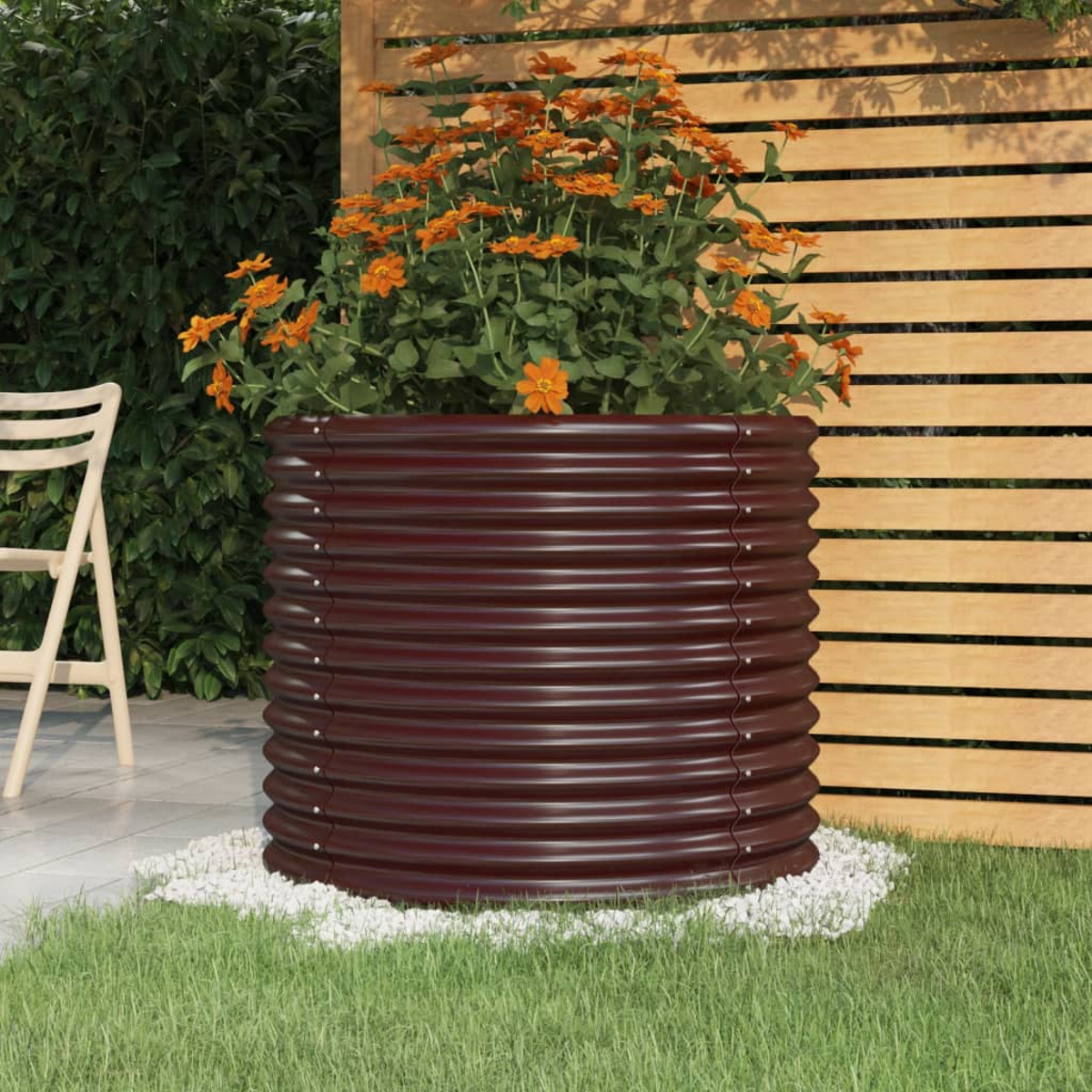 Großer, brauner, gewellter Metallpflanzkübel mit orangefarbenen Blumen in einer Gartenumgebung.