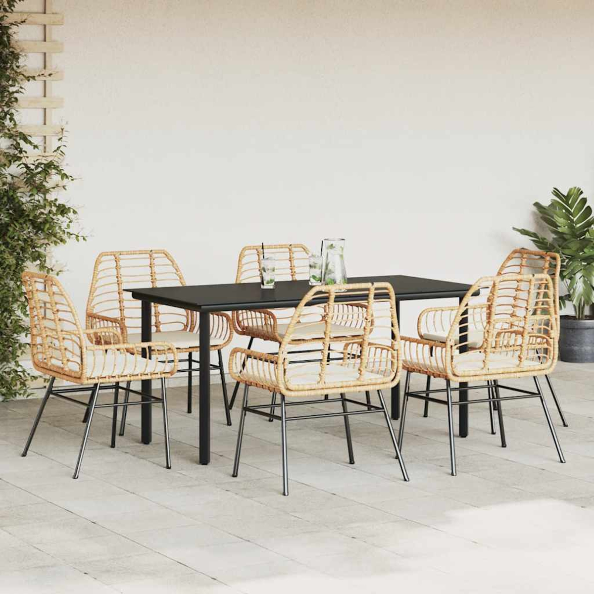 Set da pranzo per esterni con sedie in vimini, tavolo nero e piante.