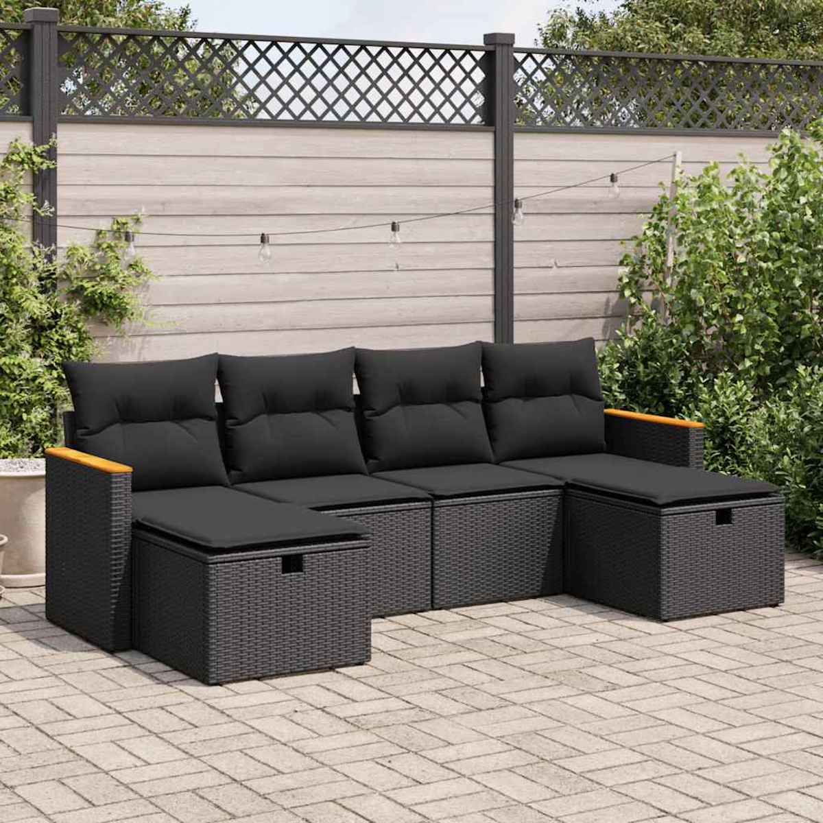 Schwarzes Rattan-Ecksofa mit schwarzen Kissen und Holzarmlehnen. Es steht auf einer Ziegelterrasse.