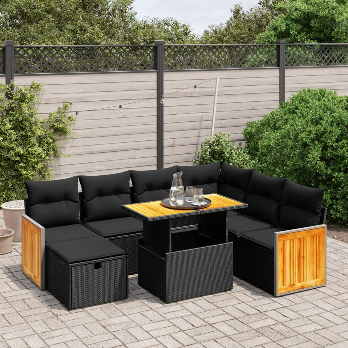 Terrassen-Set mit schwarzen Korbmöbeln, Tisch und Sofa, mit Holzzaun.