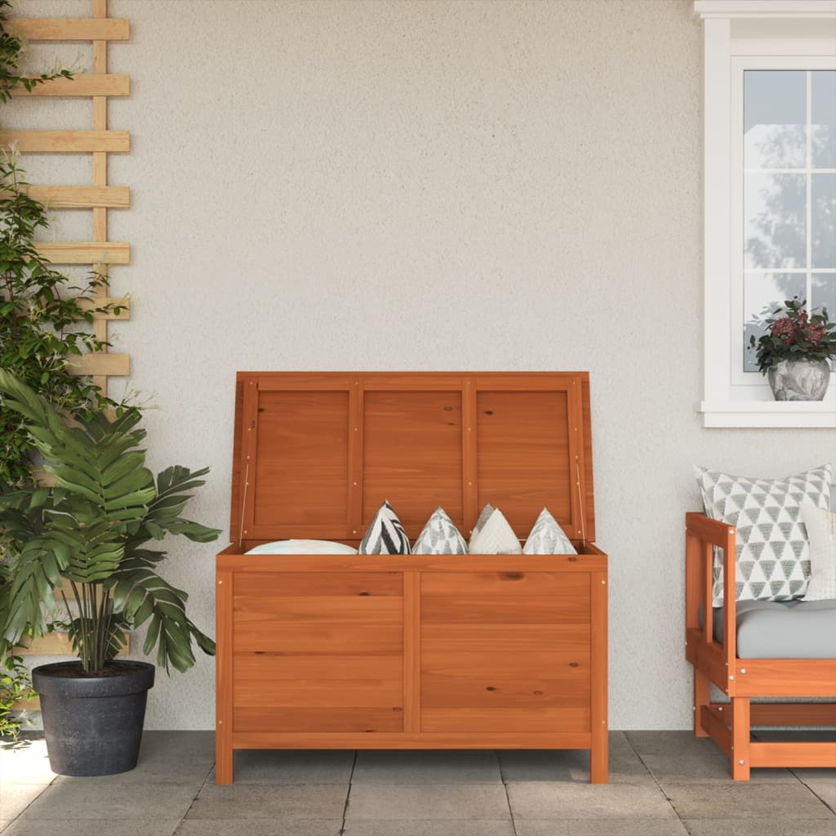 Holzkiste mit offenem Deckel. Innen befinden sich Kissen. Neben einer Pflanze, auf einer Terrasse.