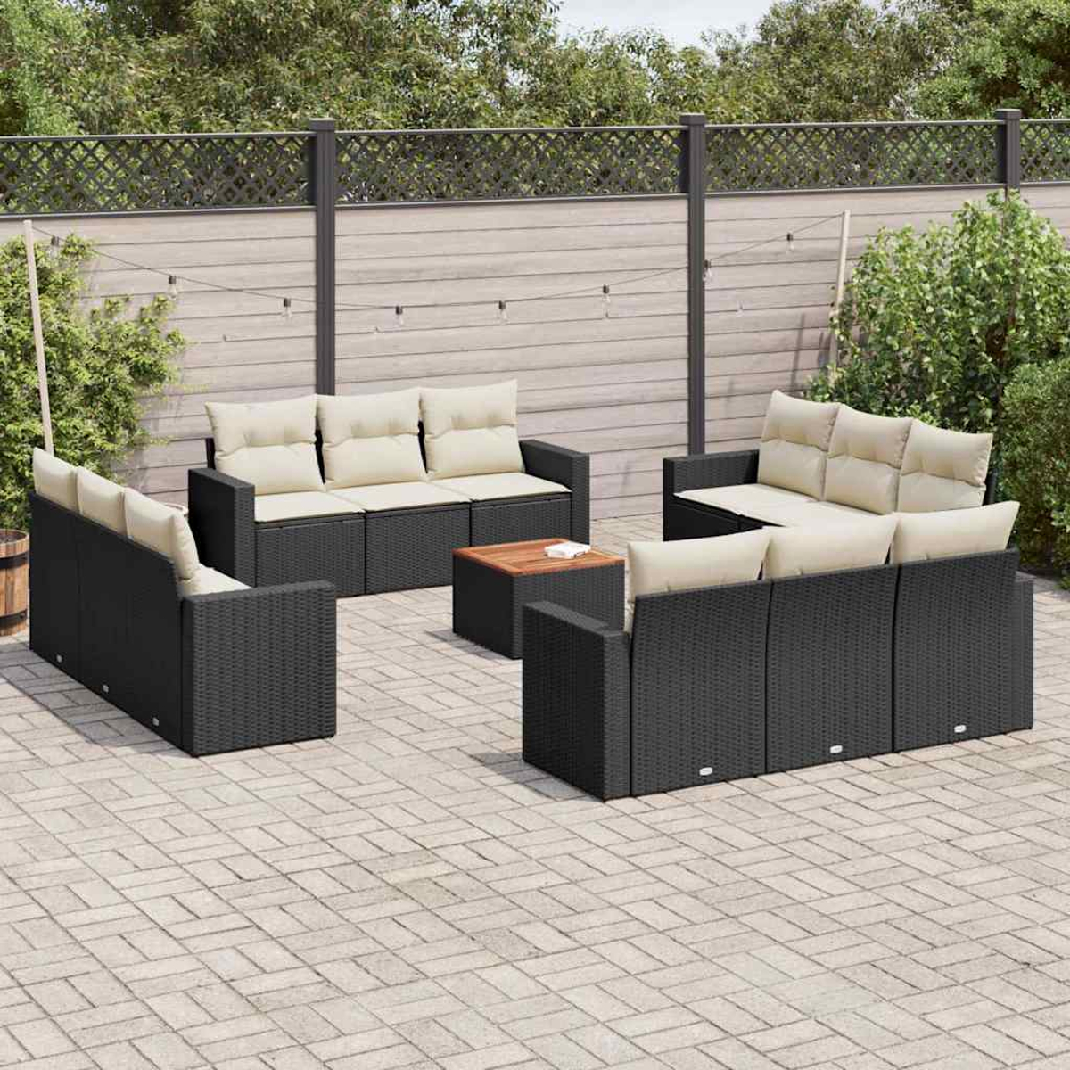 Schwarzes Outdoor-Ecksofa mit beigen Kissen auf einer Backstein-Terrasse. Ein Holztisch steht im Zentrum.