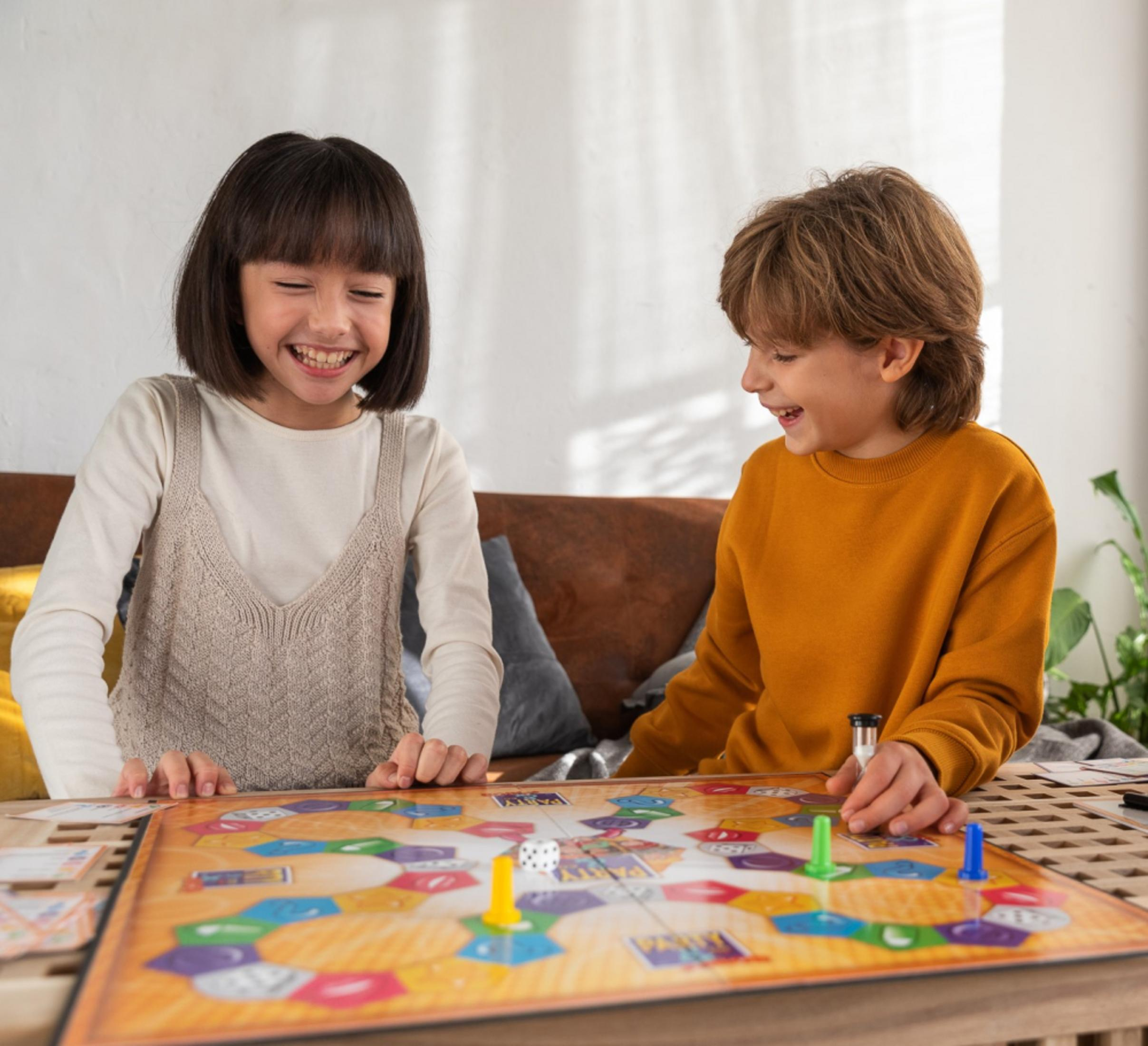 Zwei Kinder spielen ein Brettspiel, lächeln und lachen.