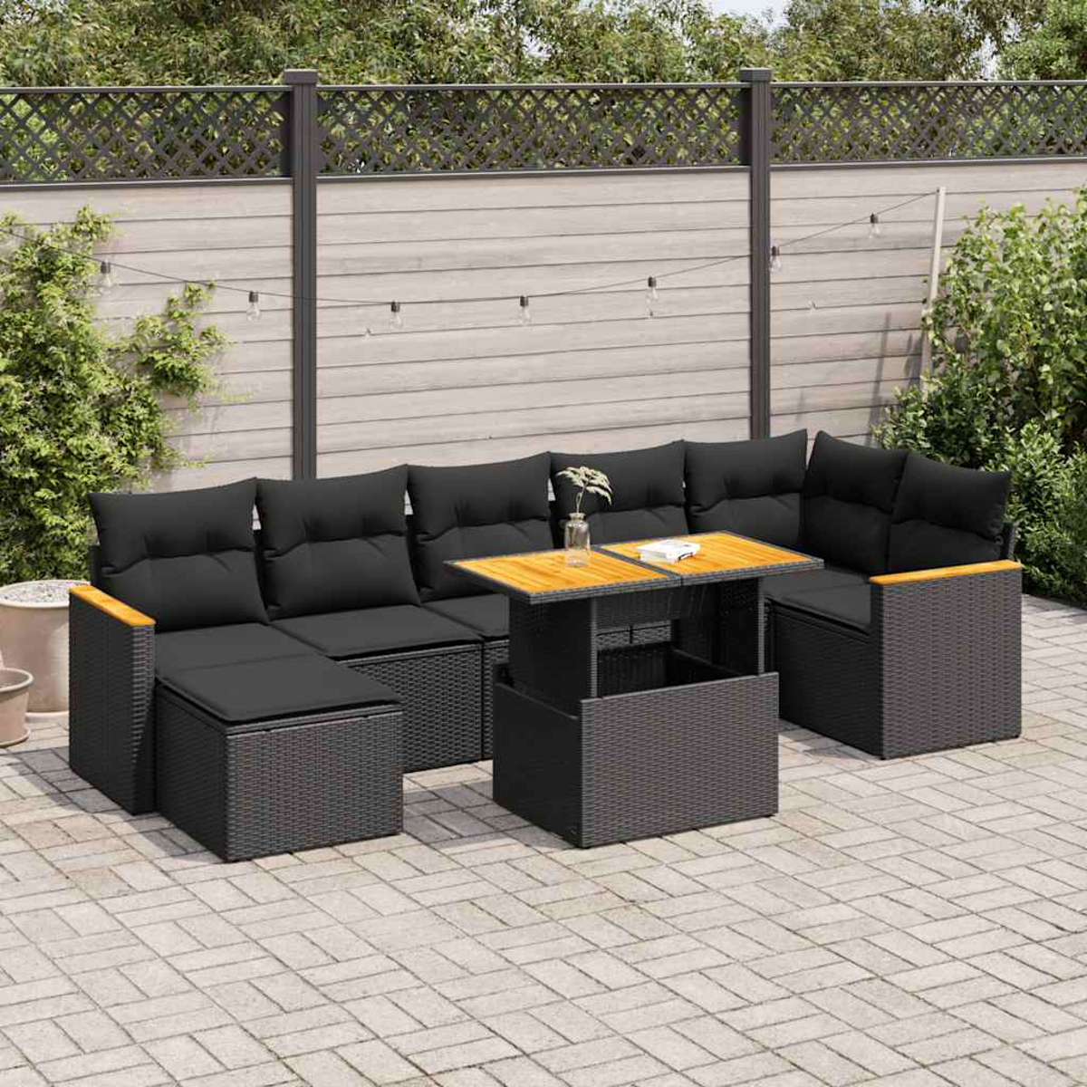 Set di mobili da esterno in vimini nero con cuscini, su un patio. Include un tavolo e un divano.