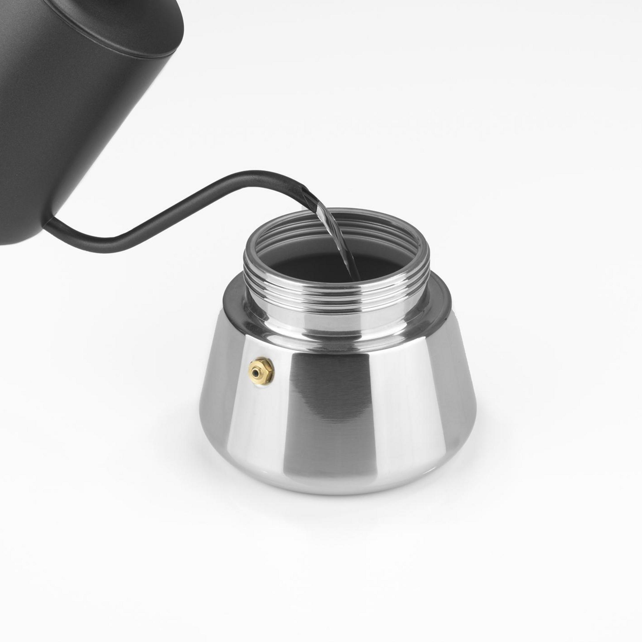 Wasser gießt in einen Espressokocher aus Edelstahl auf einem weißen Hintergrund.