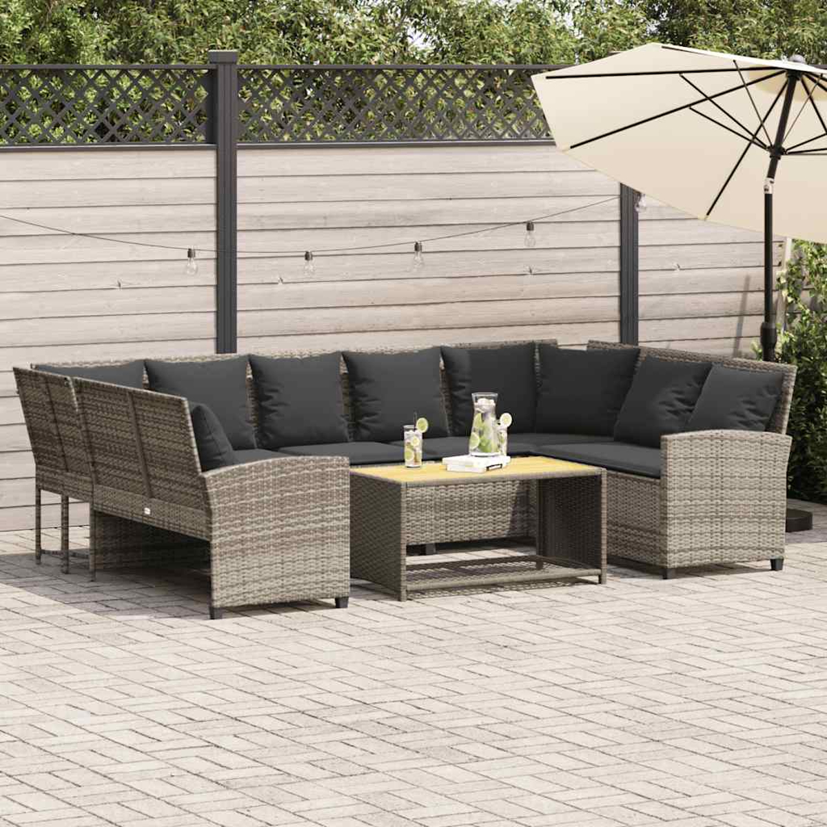 Gartenmöbel-Set mit Ecksofa, Couchtisch und Sonnenschirm. Im Hintergrund ist ein Zaun zu sehen.