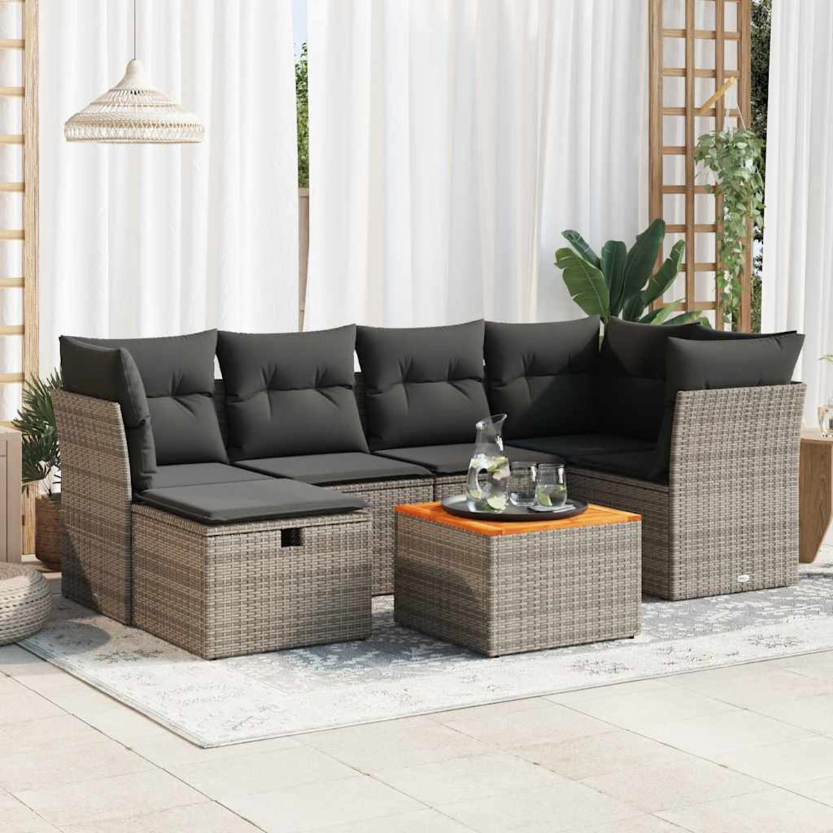 Eine Sitzgruppe im Freien mit Sofa, Couchtisch und Kissen, angeordnet auf einem Teppich.