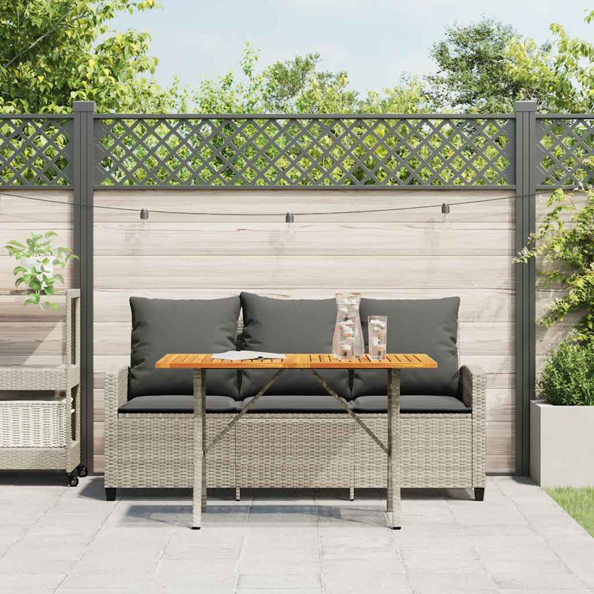 Divano in rattan con tavolo in legno e tavolo pieghevole su un patio, con piante.