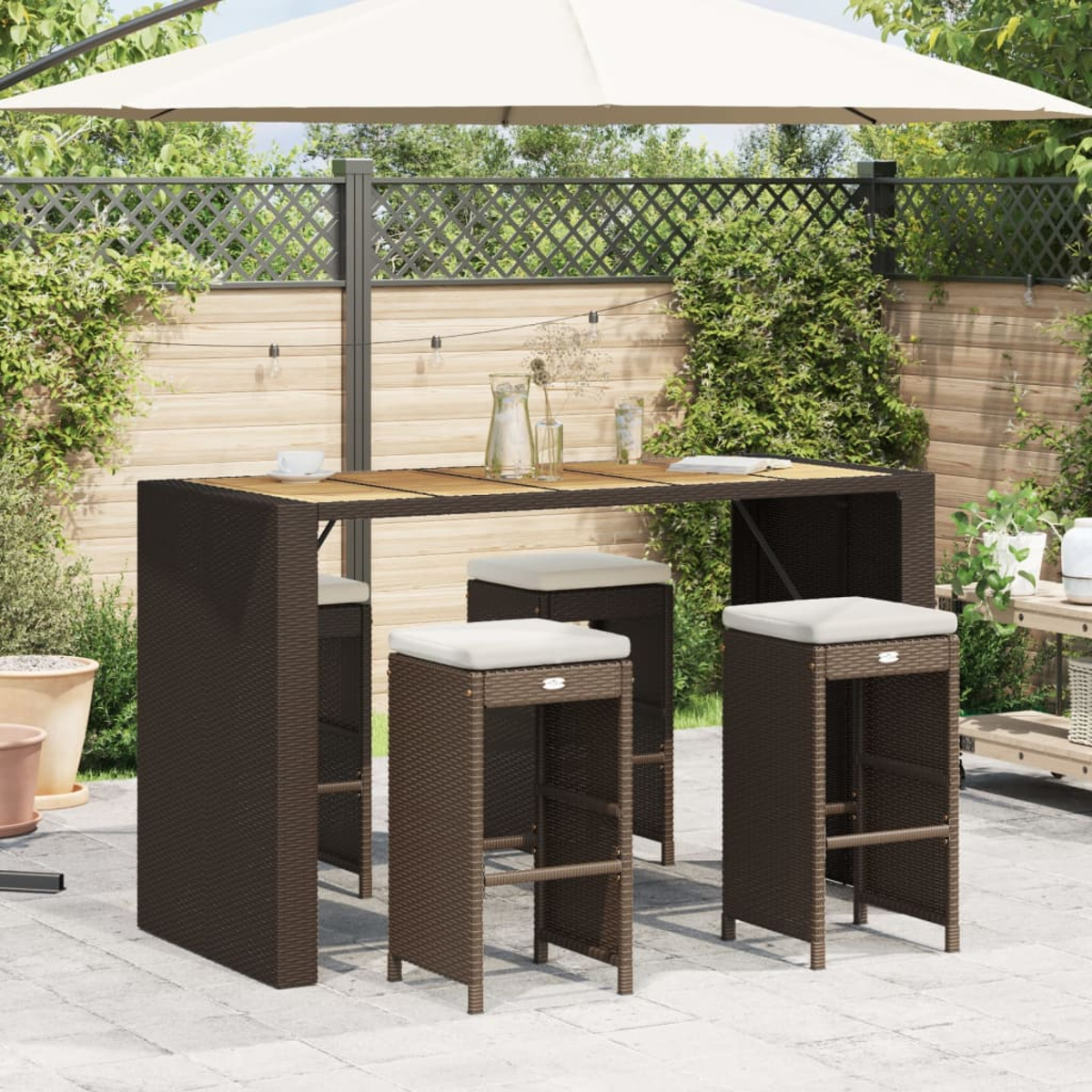 Ein Outdoor-Bartisch-Set mit einem Tisch und drei Hockern. Braune Korbmöbel auf einer Terrasse.