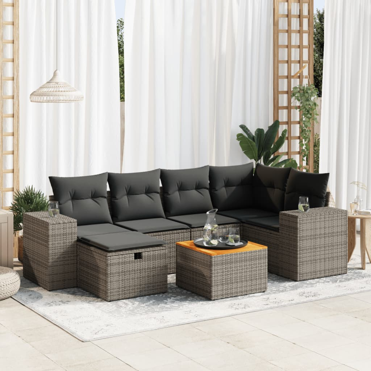 Outdoor-Terrassenset. Graues Korbmöbel-Sofa mit Kissen, Couchtisch und Beistelltischen auf einem Teppich.