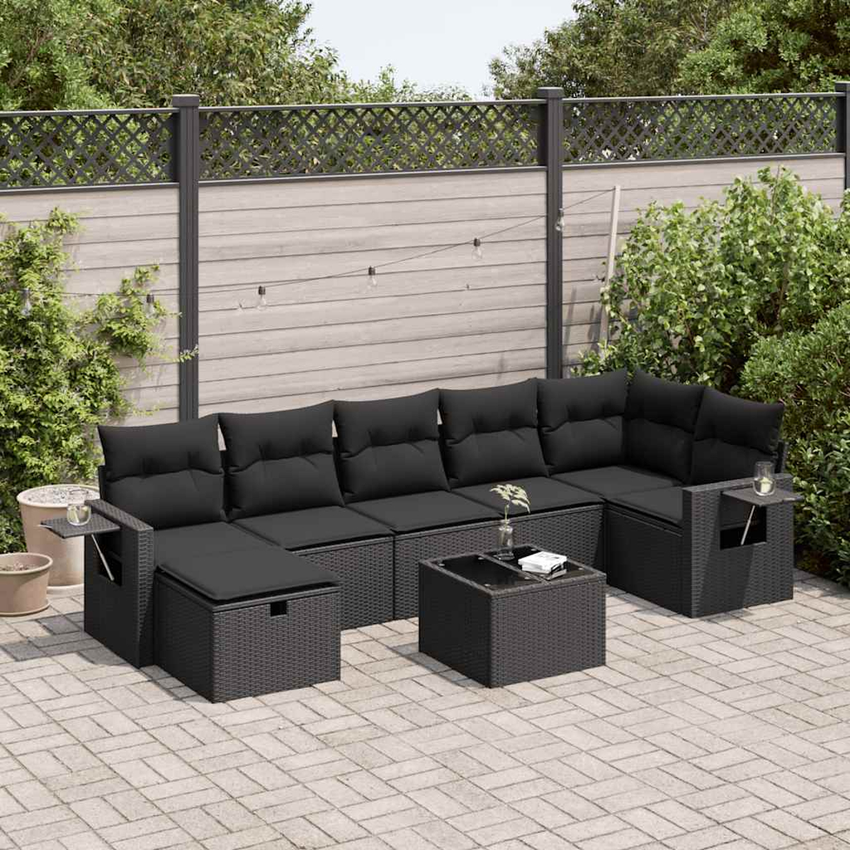 Ecksofa für den Außenbereich. Schwarze Kissen. Kleiner Tisch und Terrasse im Hintergrund. Pflanzen.