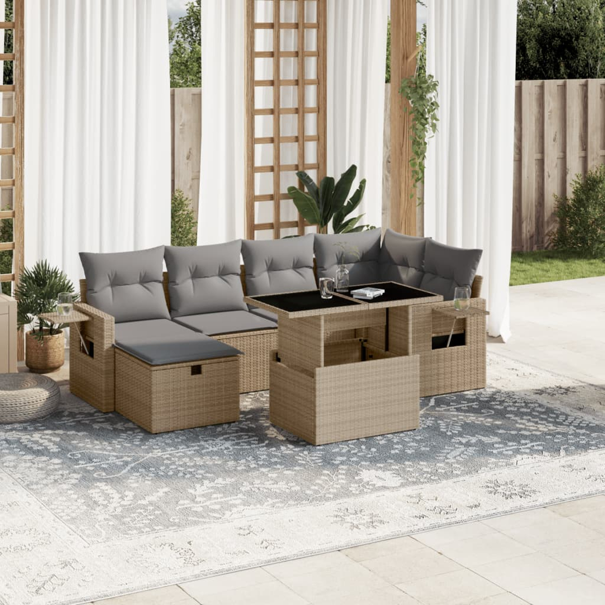 Ein Rattan-Sitzgruppe für den Außenbereich mit Tisch, Kissen, und seitlichem Stauraum, auf einem gemusterten Teppich.