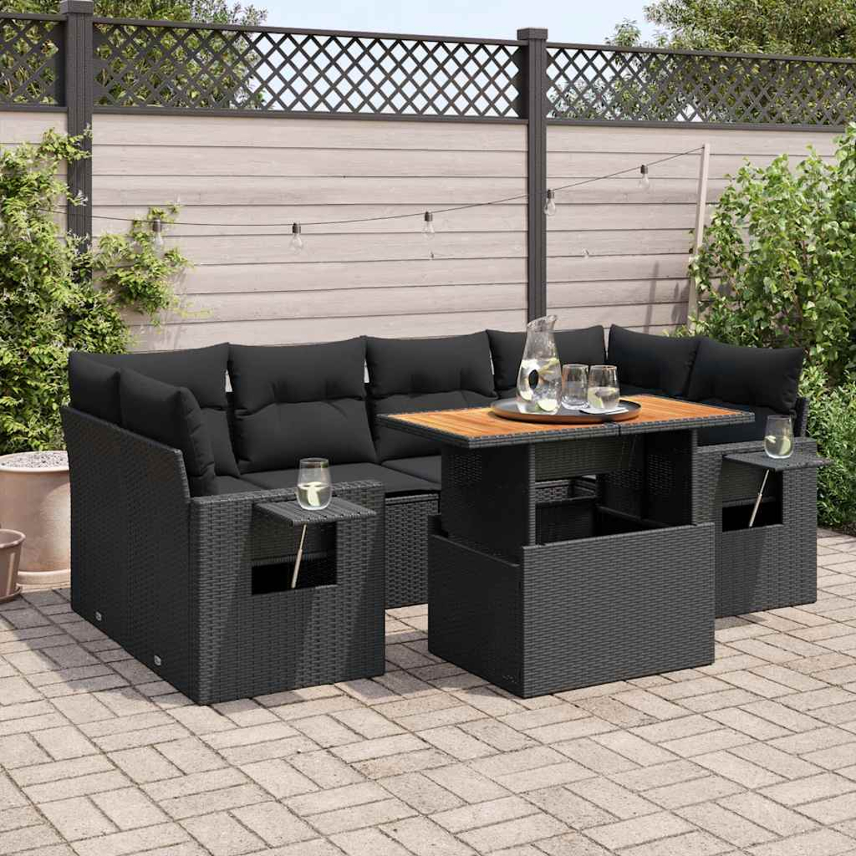Set di mobili da esterno con tavolo e divani in rattan nero con cuscini neri e dettagli in legno.