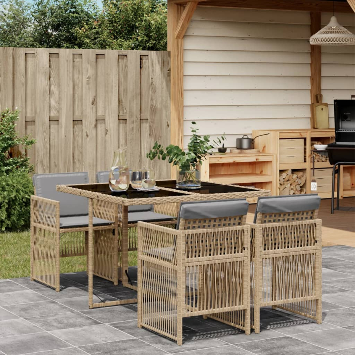 Set da pranzo all'aperto con tavolo, sedie e accessori sul patio. Mobili in vimini, cuscini grigi.