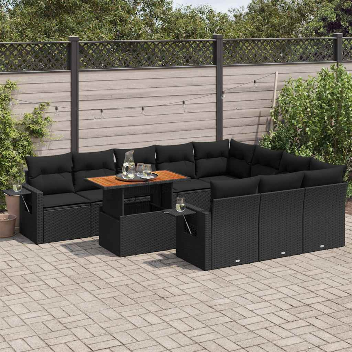 Set divano da esterno in rattan nero con tavolo su un patio. Include cuscini e bicchieri.