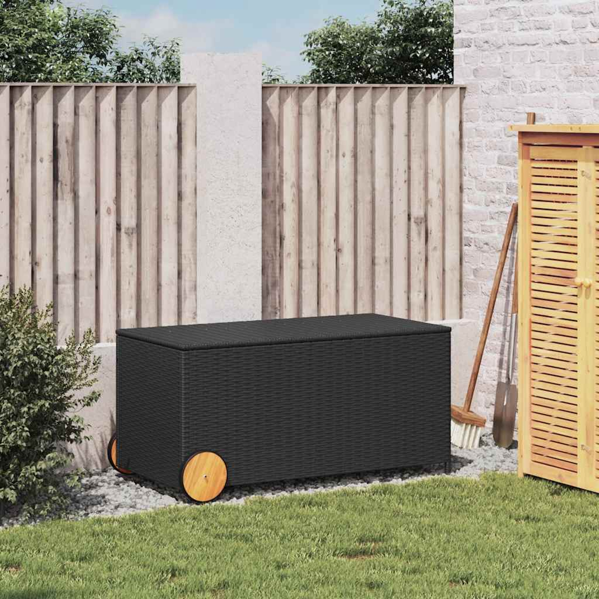 Schwarze Rattan-Aufbewahrungsbox mit Holzrädern, in einem Garten mit Zaun.