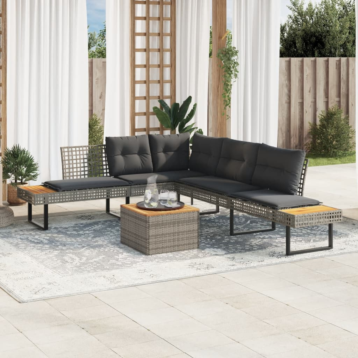 Ein Outdoor-Ecksofa mit grauen Kissen, einem Tisch und einem gemusterten Teppich.