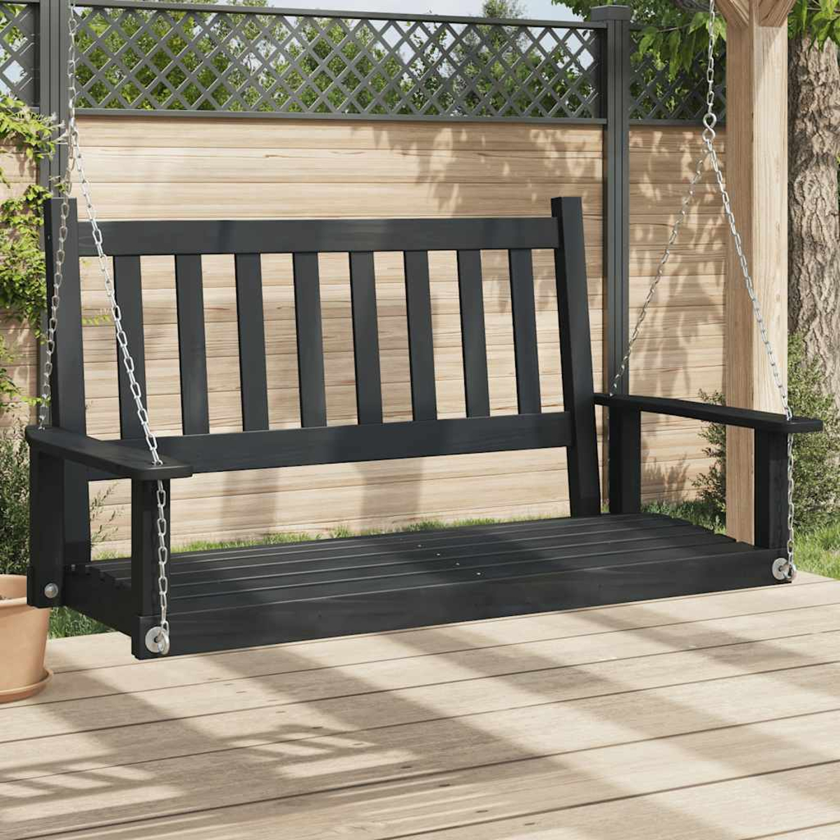 Schwarze Holzschaukel, an Ketten hängend. Hintergrund: Holzzaun und Grün.