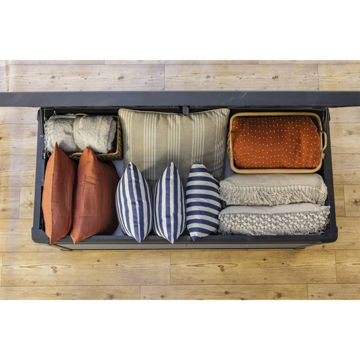 Aufbewahrungsbox mit Kissen, Decken und einem Tablett. Holzboden.