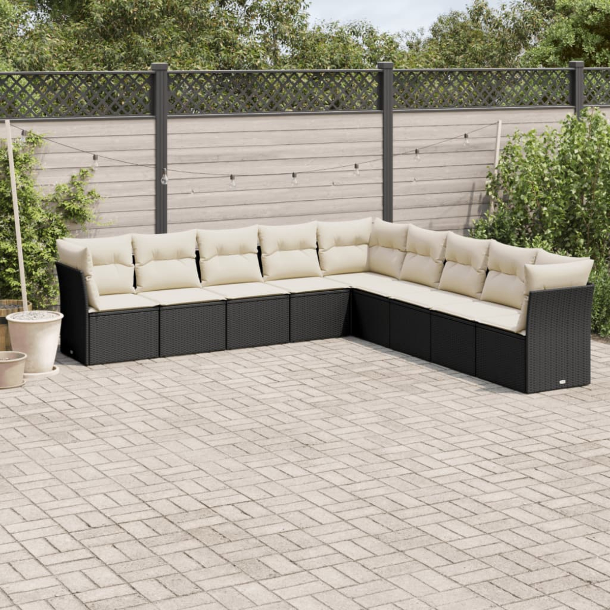 Schwarzes Korbgeflecht L-förmiges Outdoor-Sofaset mit cremefarbenen Kissen. Sonniger Tag.