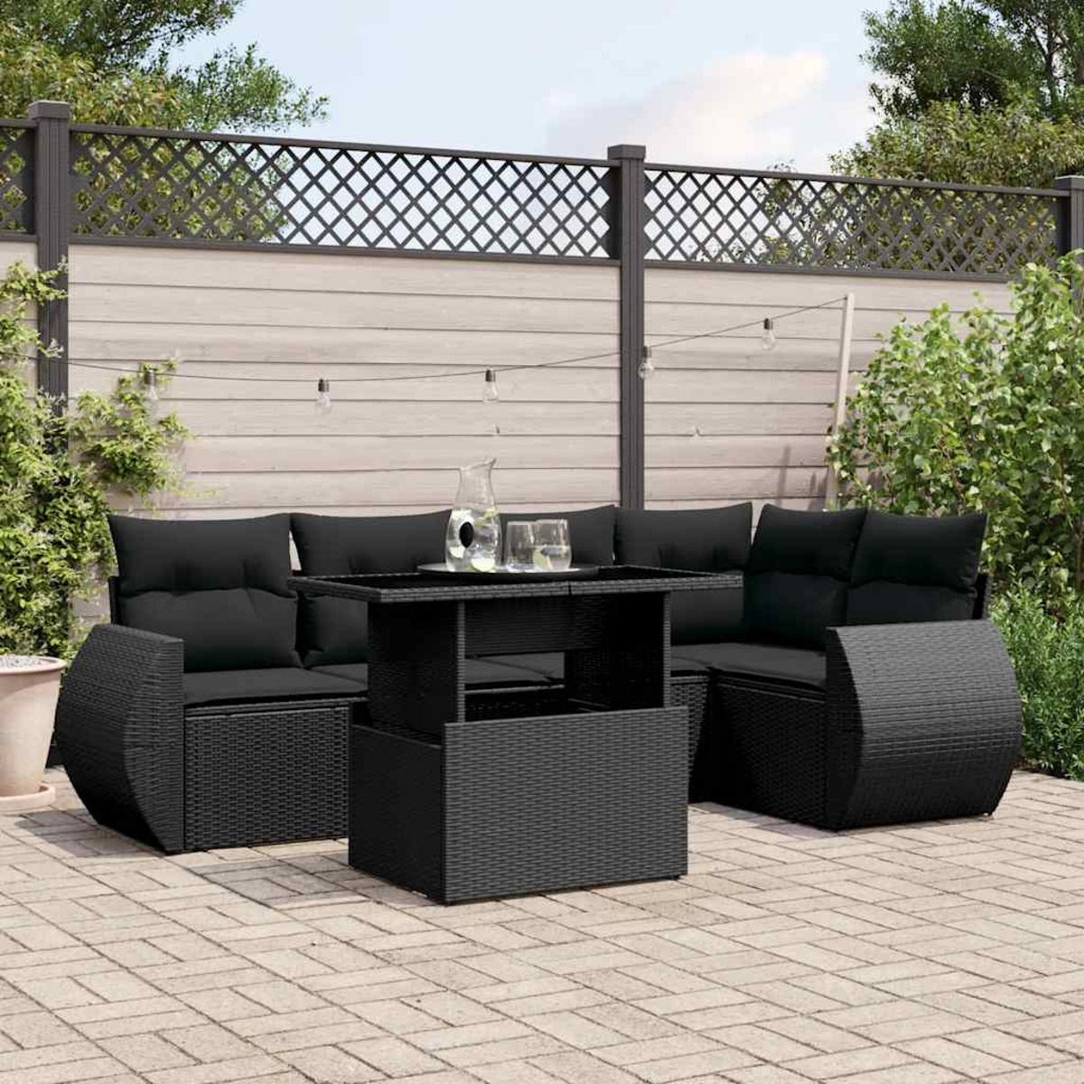 Ein schwarzes Rattan-Outdoor-Sofa-Set mit einem Tisch. Das Set steht auf einer Ziegelpflasterung.