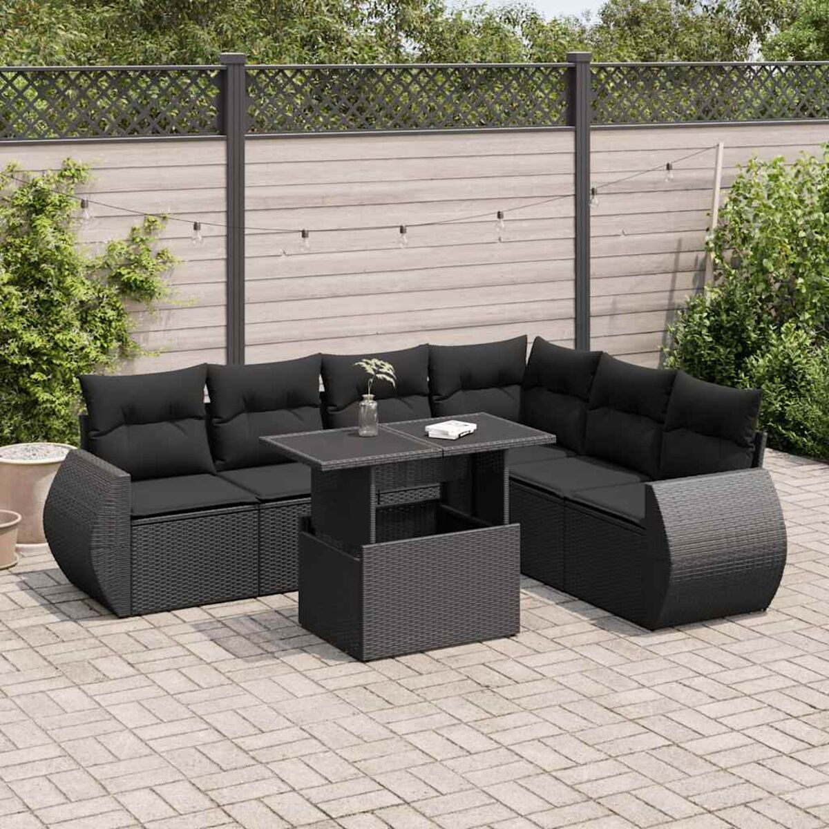 Schwarzes Rattan-Outdoor-Sofaset mit schwarzen Kissen. Der Tisch hat eine Glasplatte.