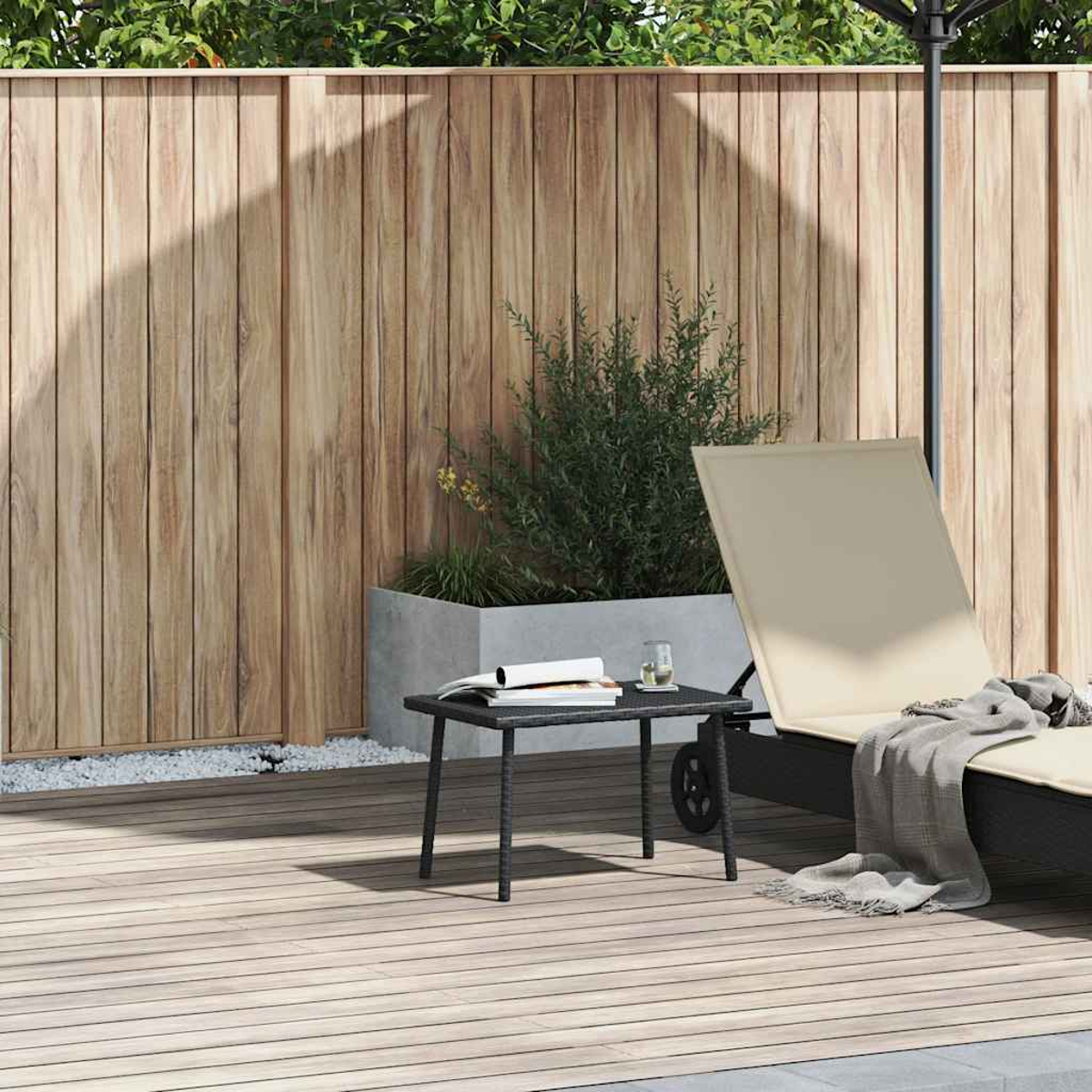 Szene im Freien mit Holzterrasse, beiger Liege, kleinem Tisch, Holzzaun und Pflanzen.