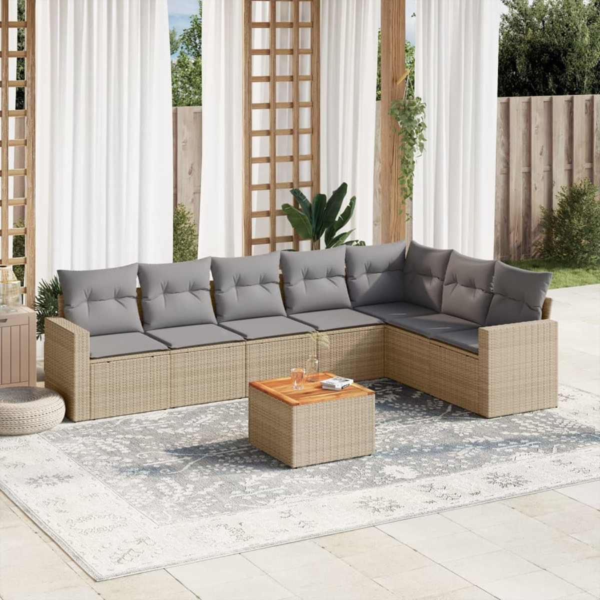 Ein hellbraunes Ecksofa aus Korbgeflecht mit grauen Kissen und einem kleinen Holztisch auf einem Teppich. Weißer Hintergrund.