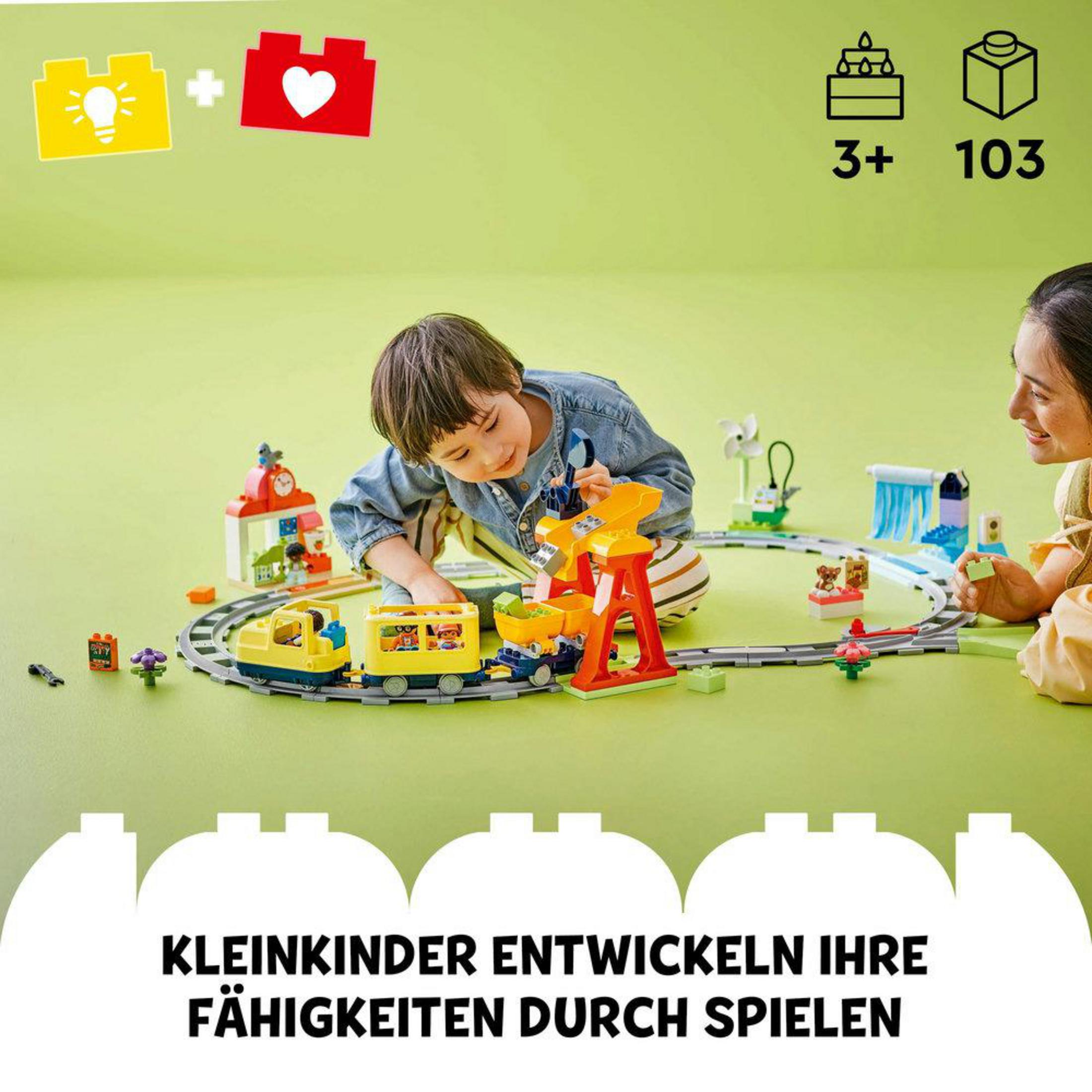 Due bambini che giocano con un trenino LEGO Duplo, che si trova su una superficie verde.