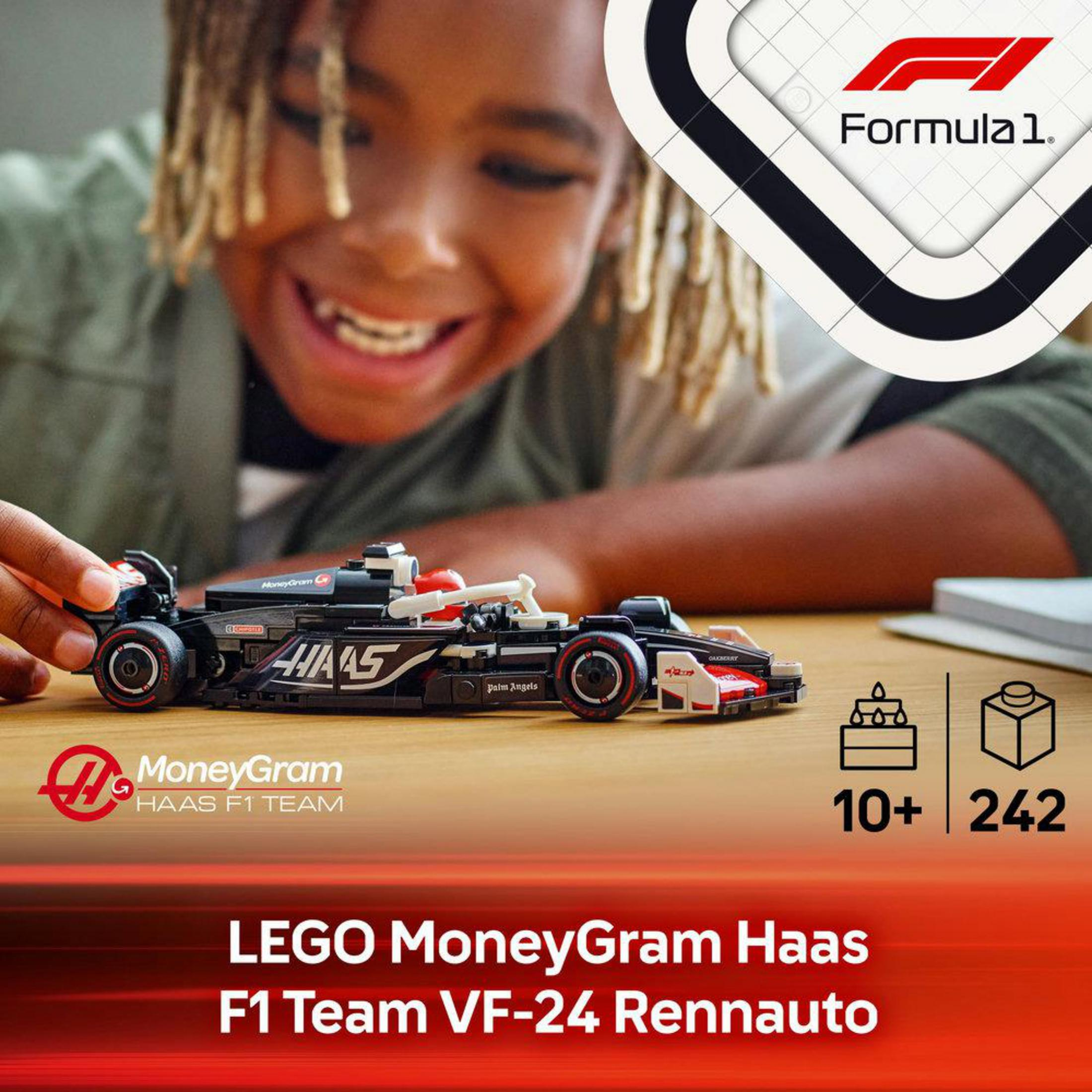 Chłopiec bawiący się samochodem wyścigowym Lego F1. Samochód jest czarny i czerwony, z logo sponsorów.