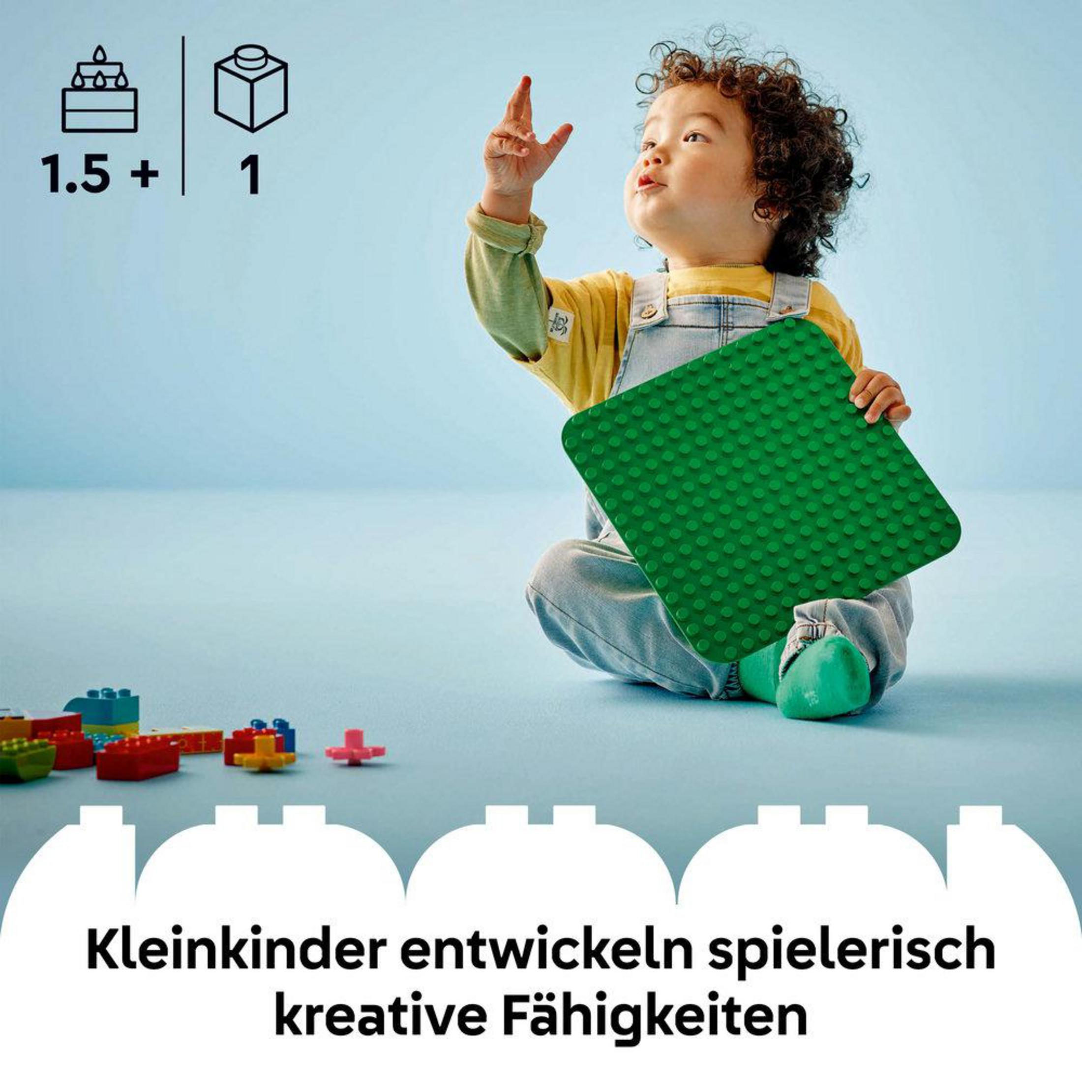 Dziecko bawiące się zieloną płytą Lego Duplo i innymi kolorowymi klockami.