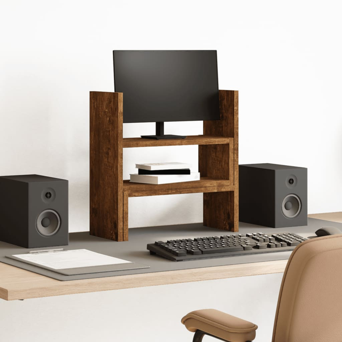 Schreibtisch-Setup mit Monitor, Lautsprechern, Tastatur und Klemmbrett auf hellem Holzschreibtisch.