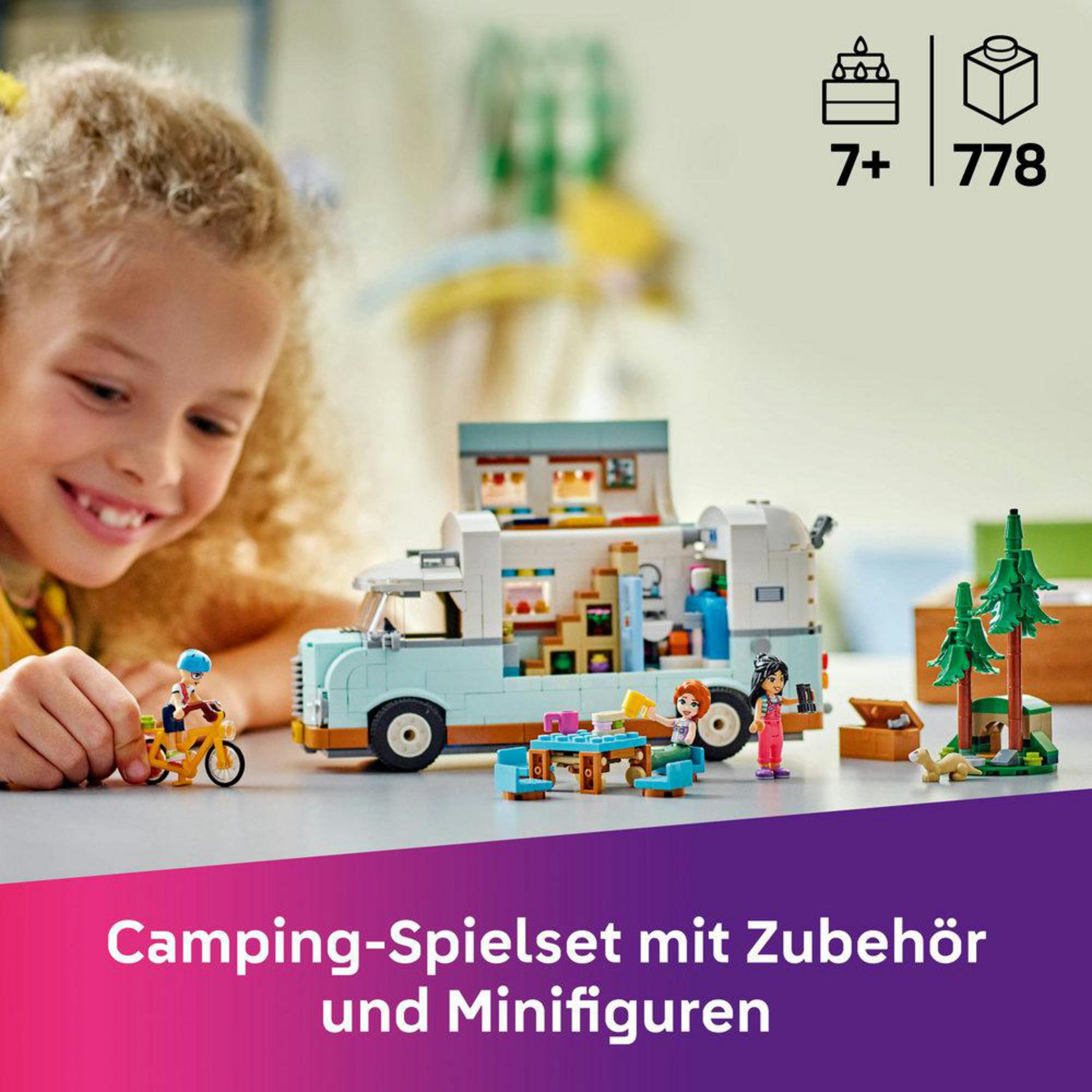 Dziewczynka uśmiecha się do zestawu LEGO z kamperem, miniaturowymi figurkami i małym rowerem.