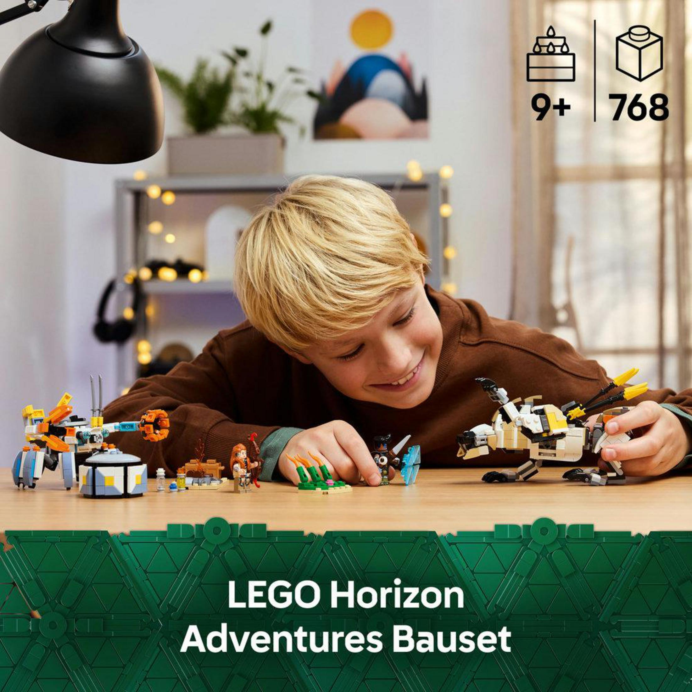 Un niño sonríe mientras construye un set LEGO Horizon Adventures sobre una mesa.