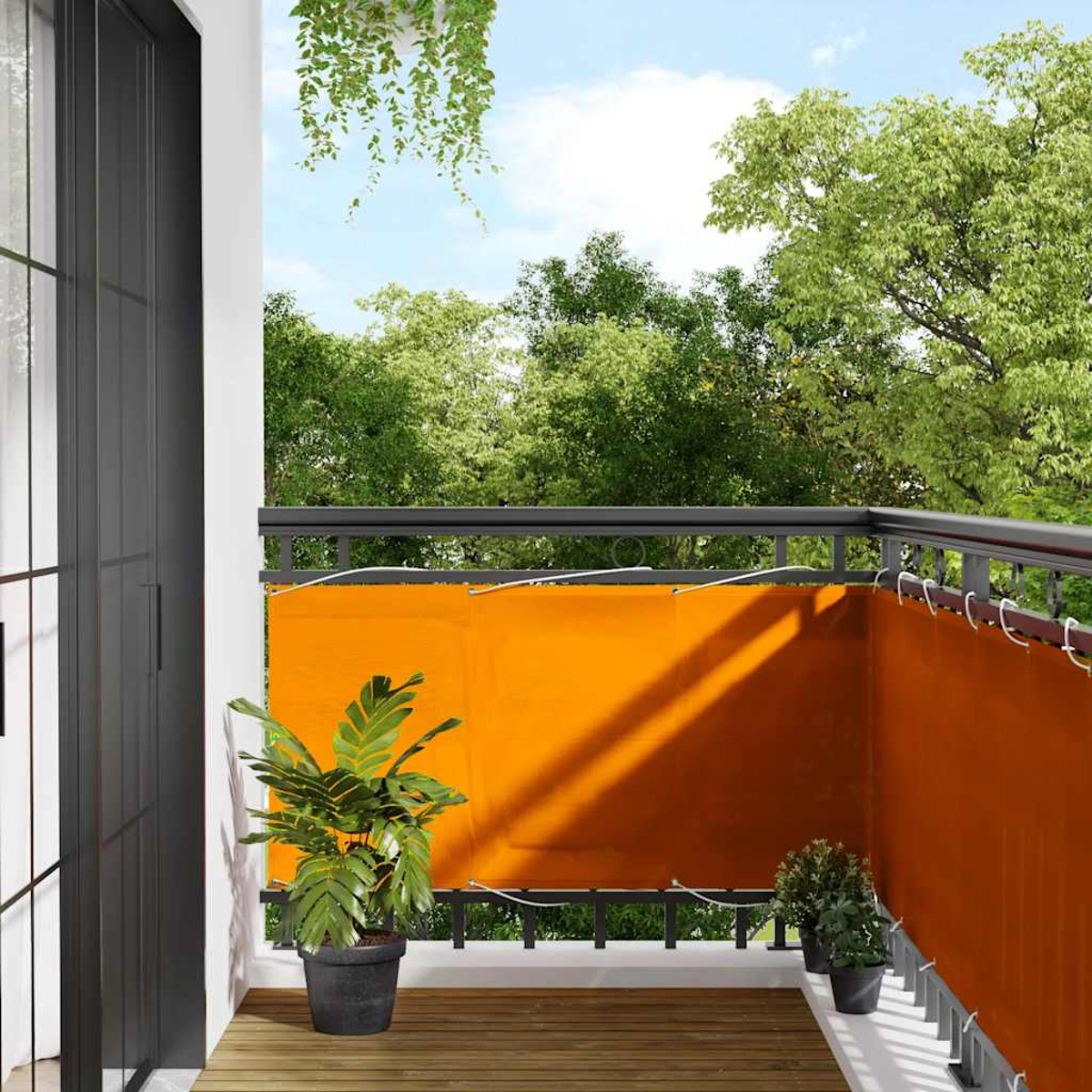 Balcone con schermo arancione, piante in vaso e pavimento in legno.