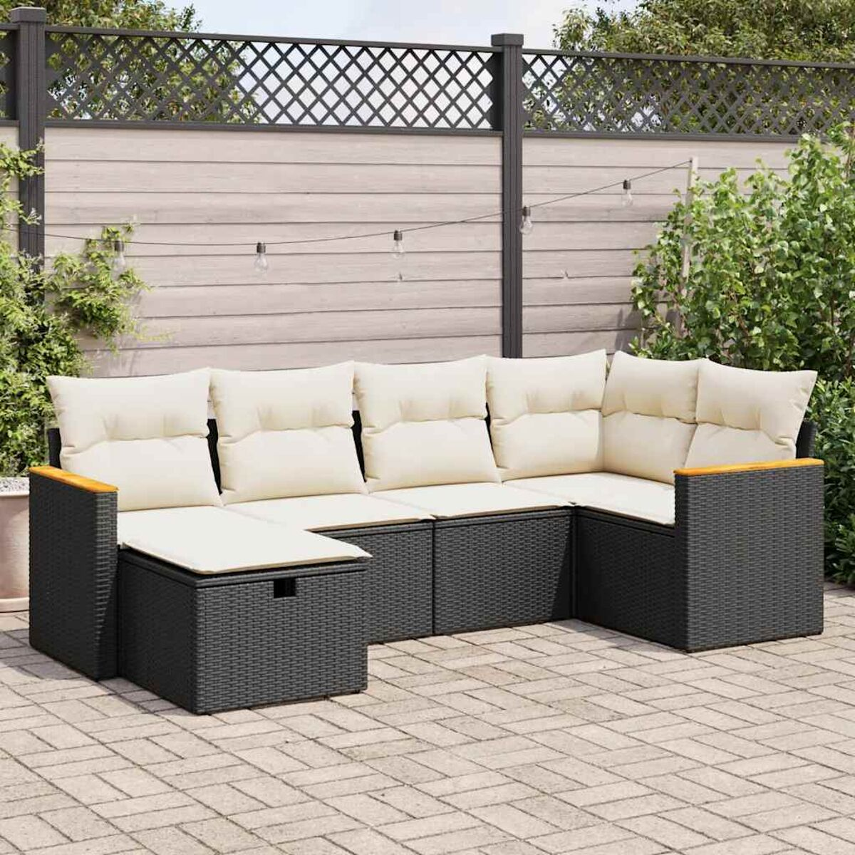 Divano ad angolo in vimini per esterni con cuscini color crema, su un patio in mattoni.