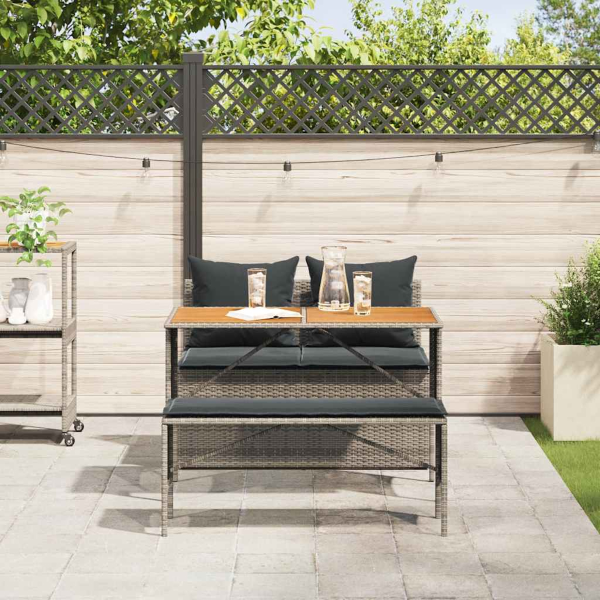 Set da pranzo all'aperto. Tavolo con 2 panche e 2 sedie. Ambiente cortile con recinzione in legno e piante.