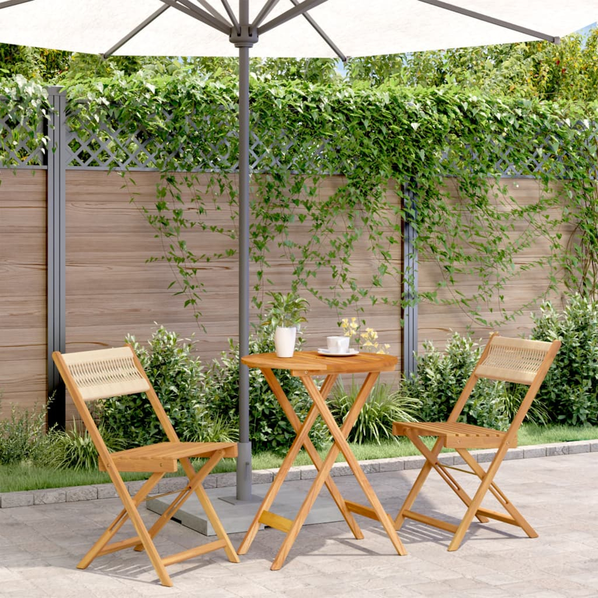 Holztisch mit zwei Stühlen und einem Sonnenschirm. Hintergrund: Terrasse und Grün.