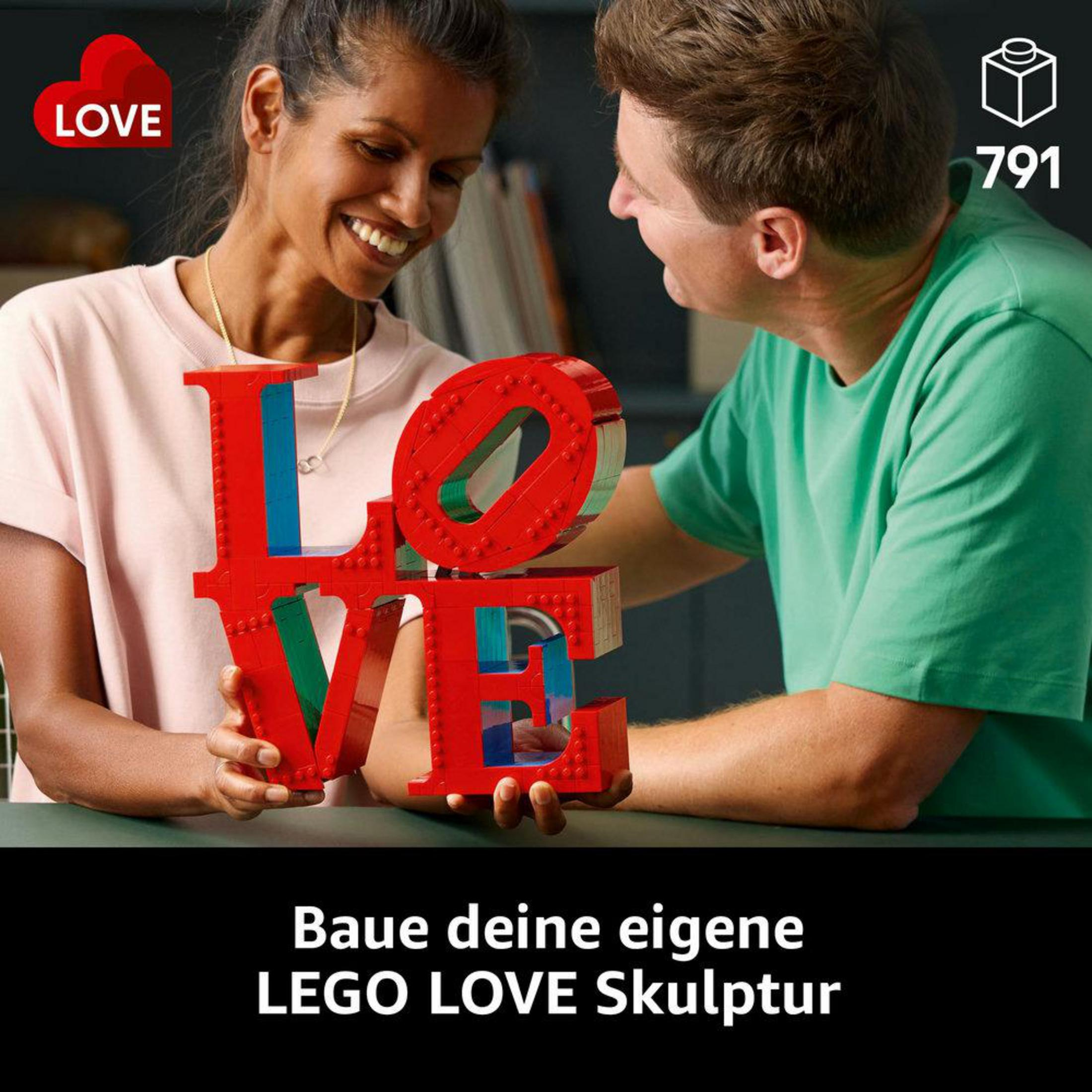 Dwie osoby budują czerwoną rzeźbę LOVE z Lego, uśmiechając się do siebie.