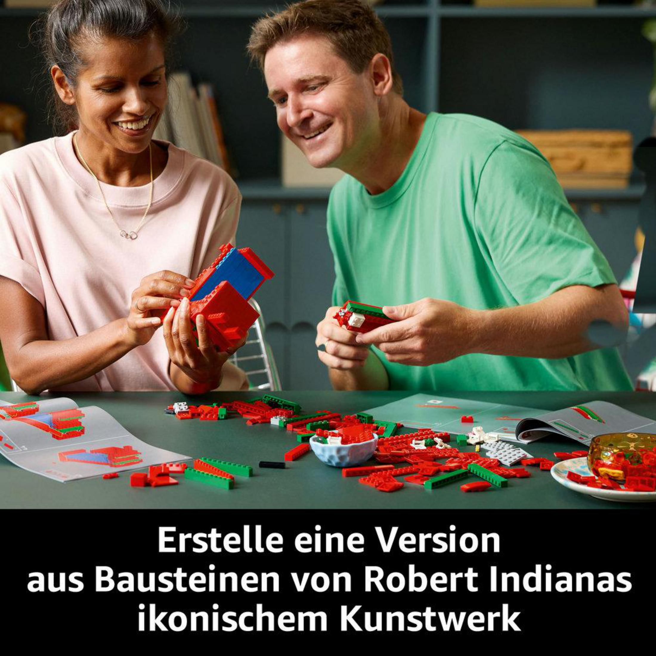 Dwie osoby składające klocki Lego, aby zbudować czerwoną rzeźbę LOVE na stole.