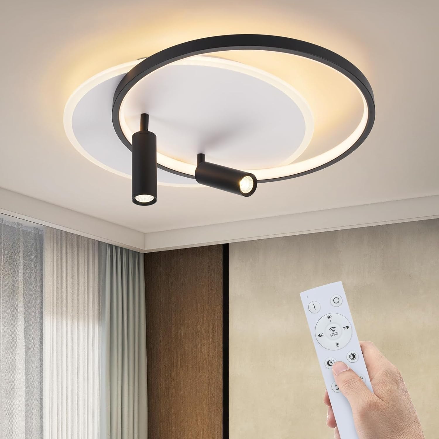 Lampada da soffitto con superfici circolari nere e bianche e due faretti neri. Una mano tiene un telecomando.