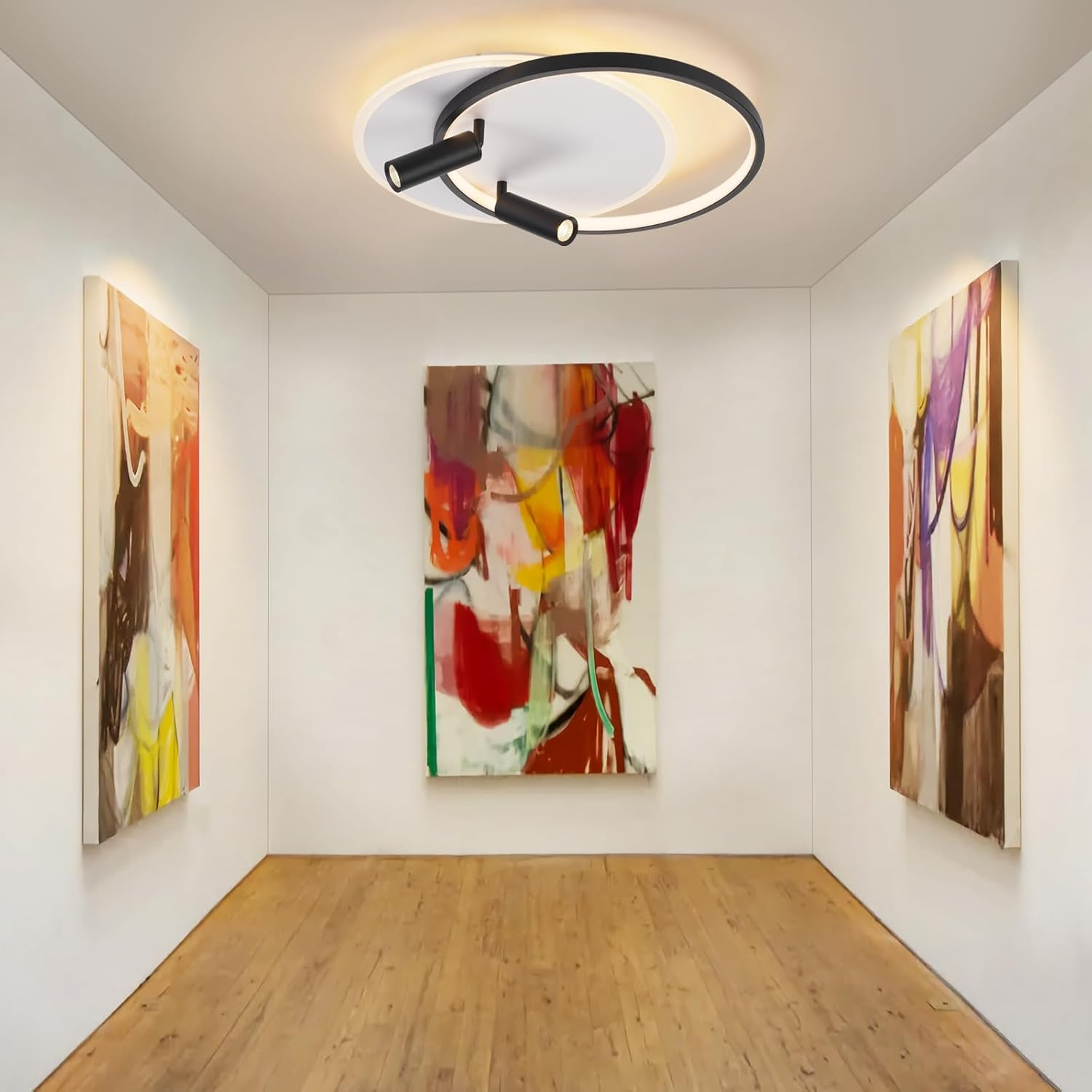 Un corridoio con tre dipinti astratti, pavimento in legno e un lampadario a soffitto.