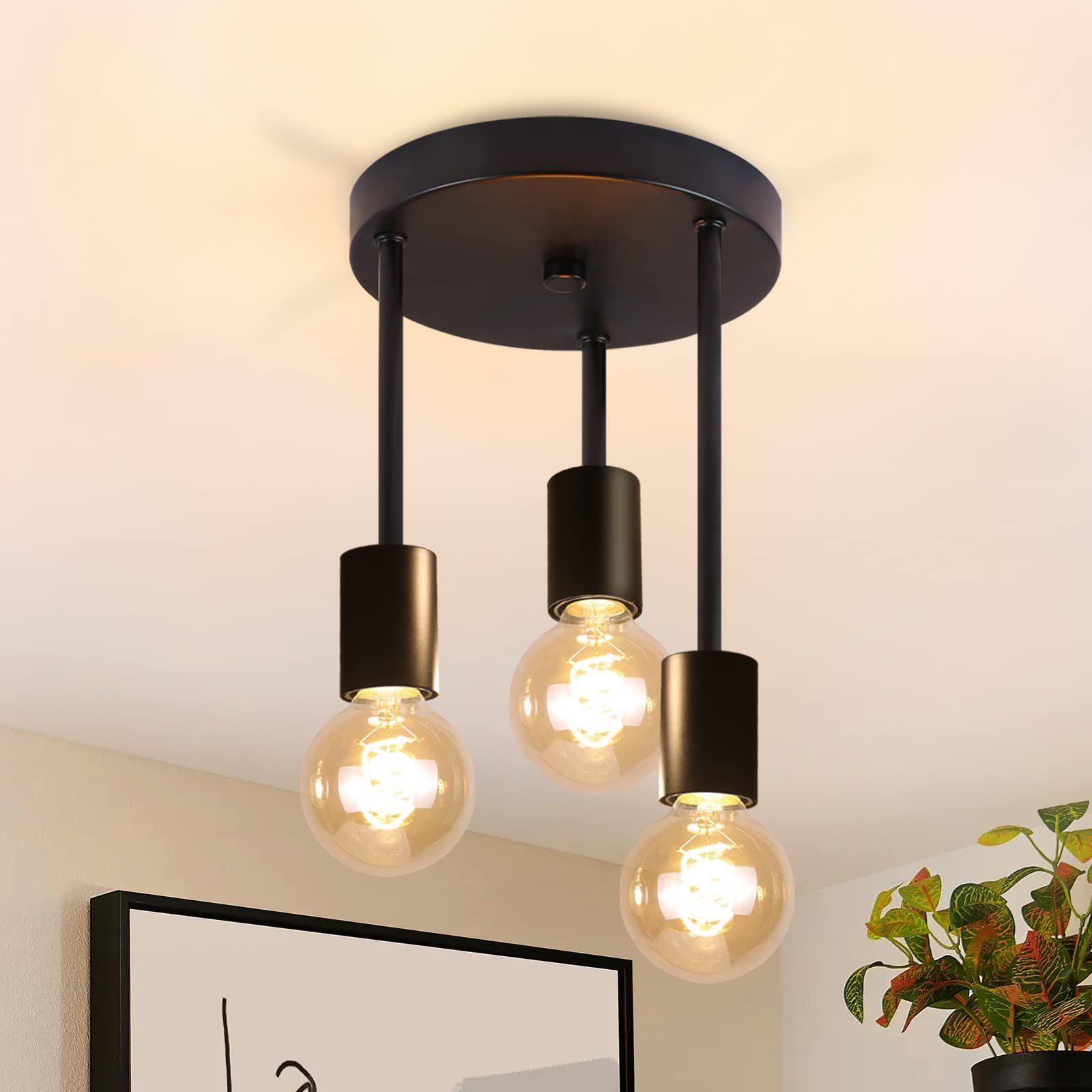 Drei schwarze Pendelleuchten mit klaren Glühbirnen, die von einer weißen Decke hängen. In einer Raumeinstellung sichtbar.