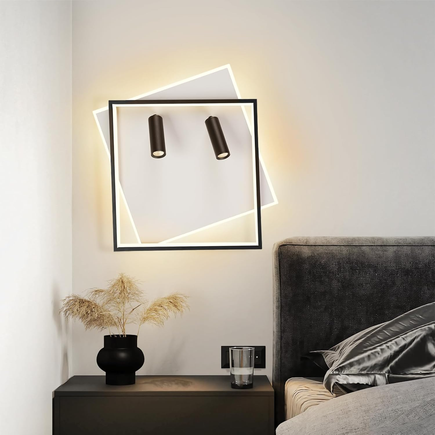 Apparecchio di illuminazione a parete bianco e nero. Dispone di due faretti e una piccola pianta sul comodino.