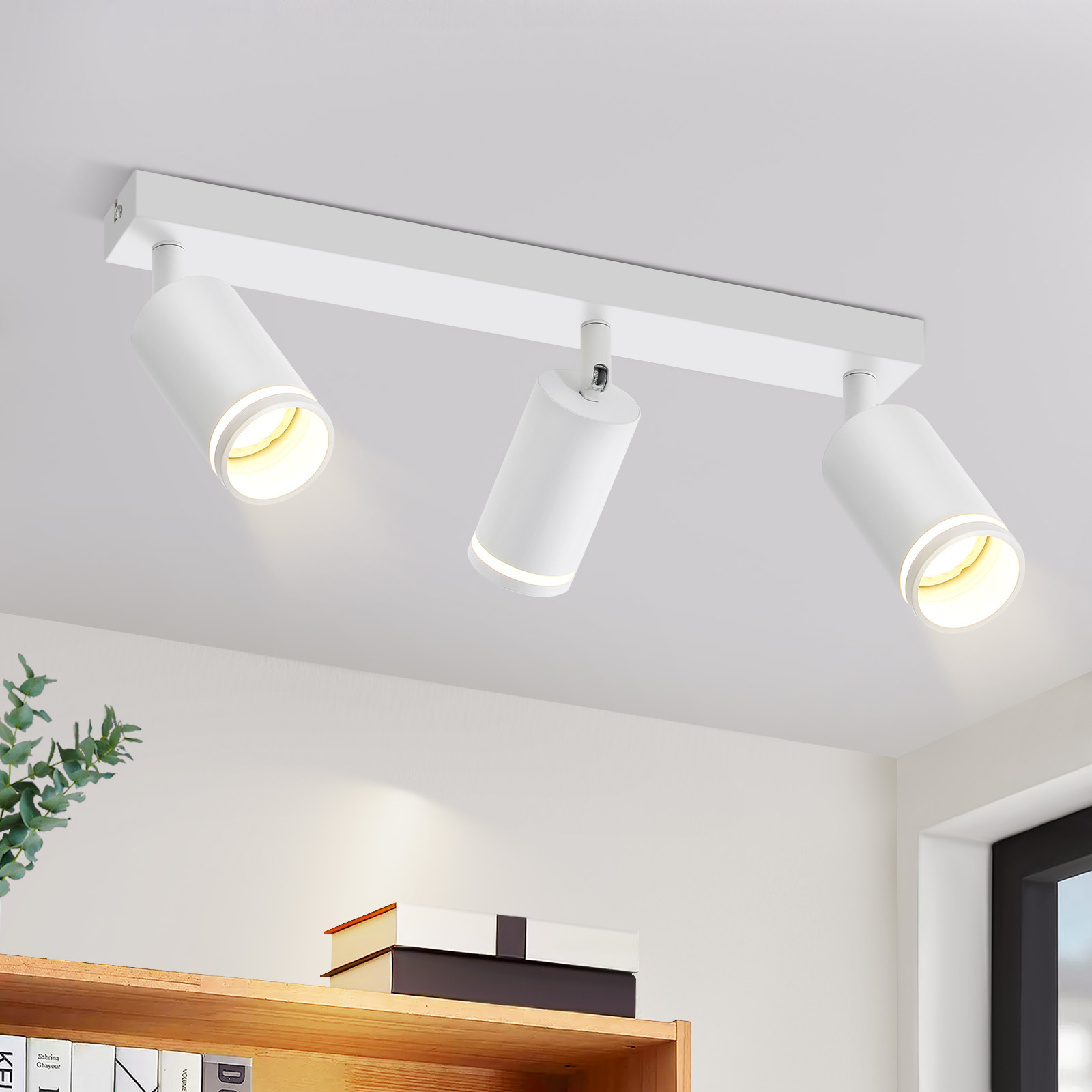 Biała lampa szynowa z trzema reflektorami na białym suficie, widok z dołu.