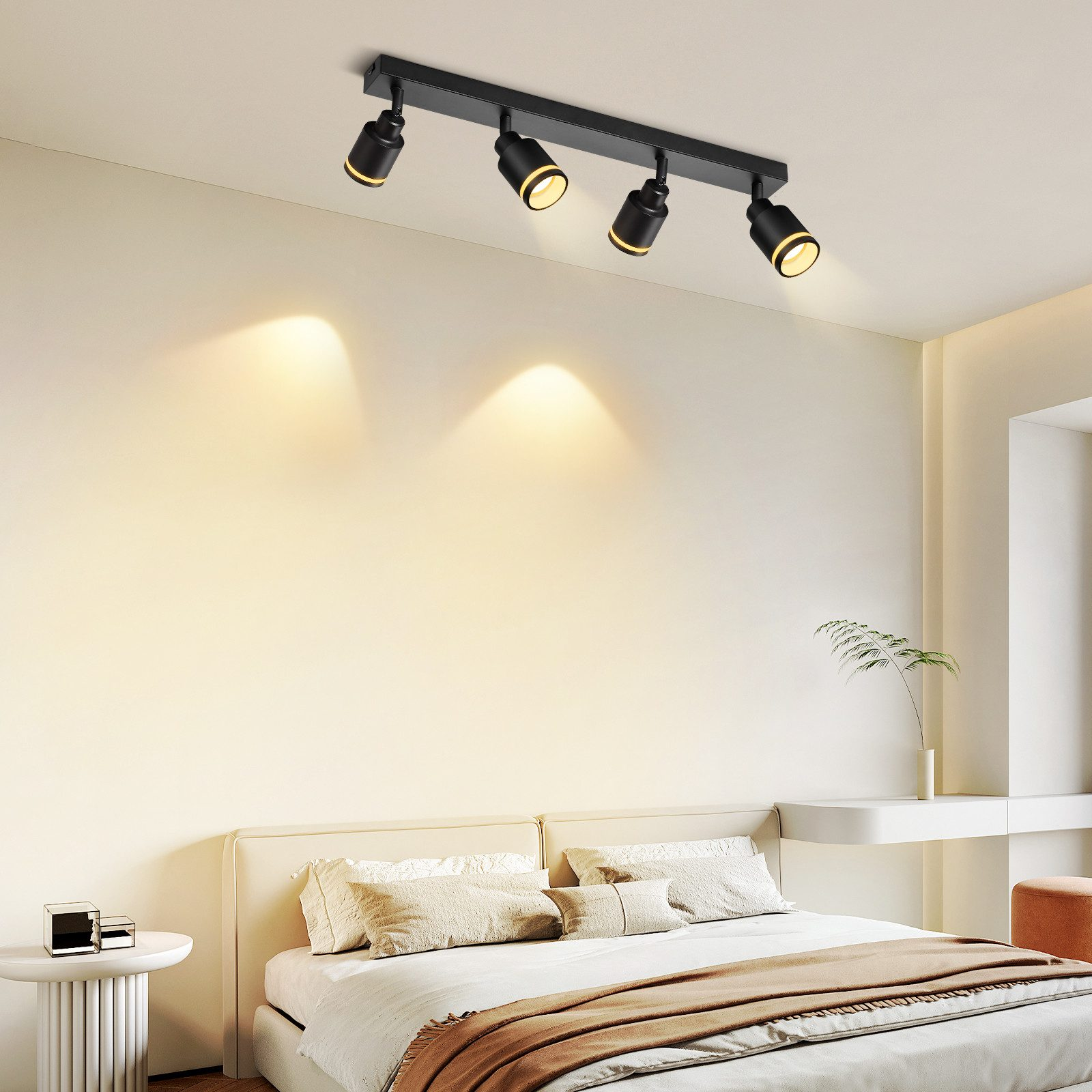 Una camera da letto con un letto, un muro bianco e faretti neri.