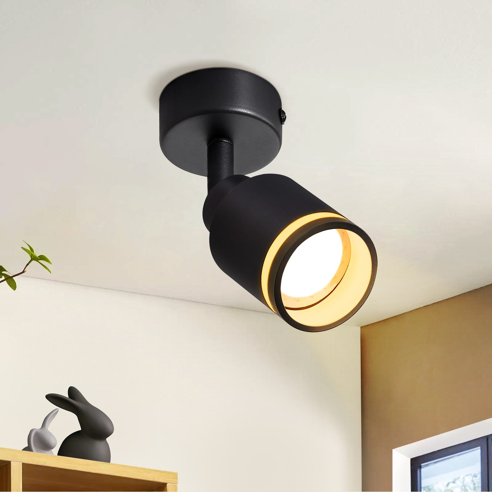 Faretto nero montato su un soffitto bianco, che illumina lo spazio.
